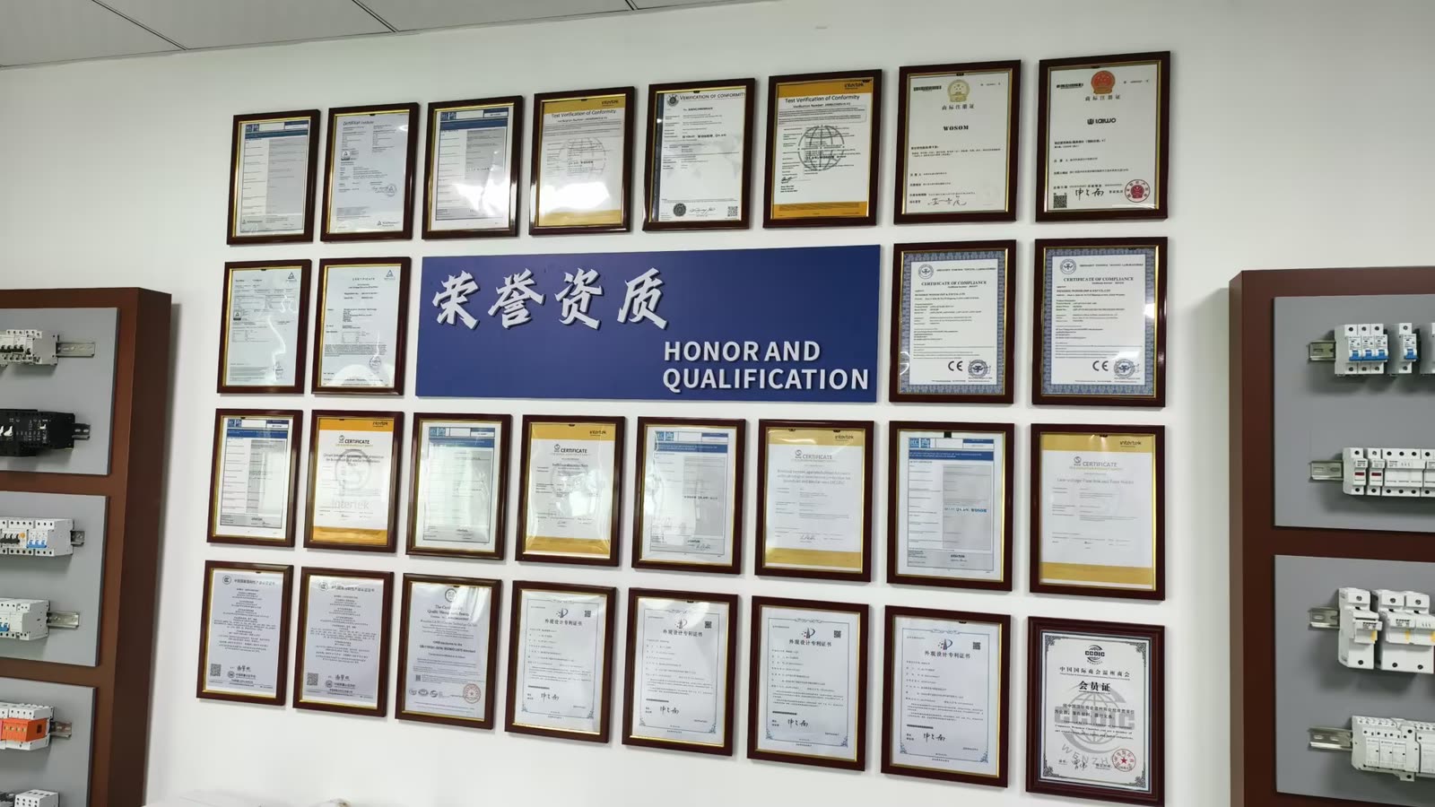 Certificates and test reports displayed on the wall at the LAIWO factory, with circuit protection product boards either side