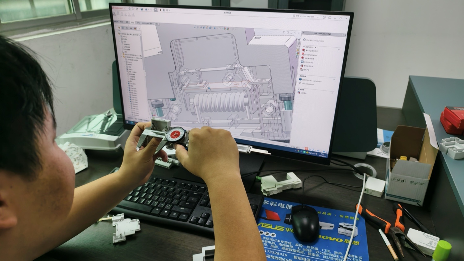 Engineer working on a 3D tooling model, holding the moulded part it produces