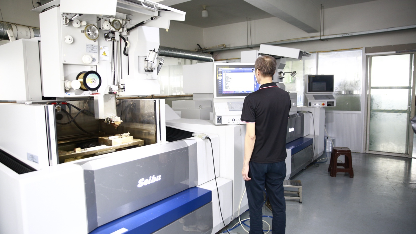 Engineer at the control panel of a wire-cut machine in the tool room